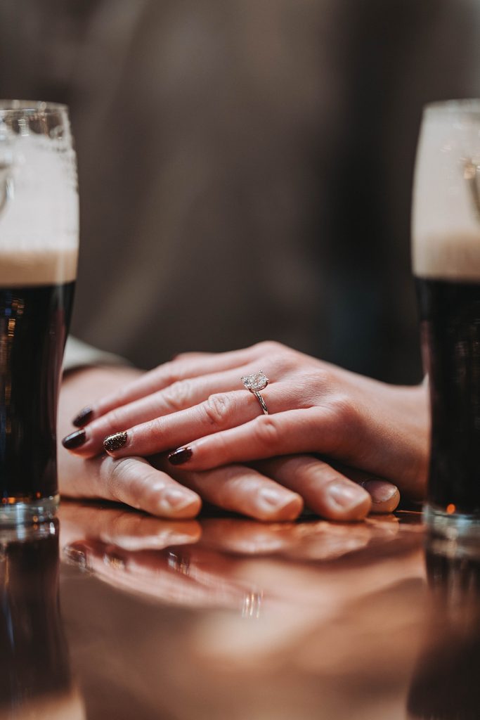 Couple holding handing and showing off engagement ring for camera